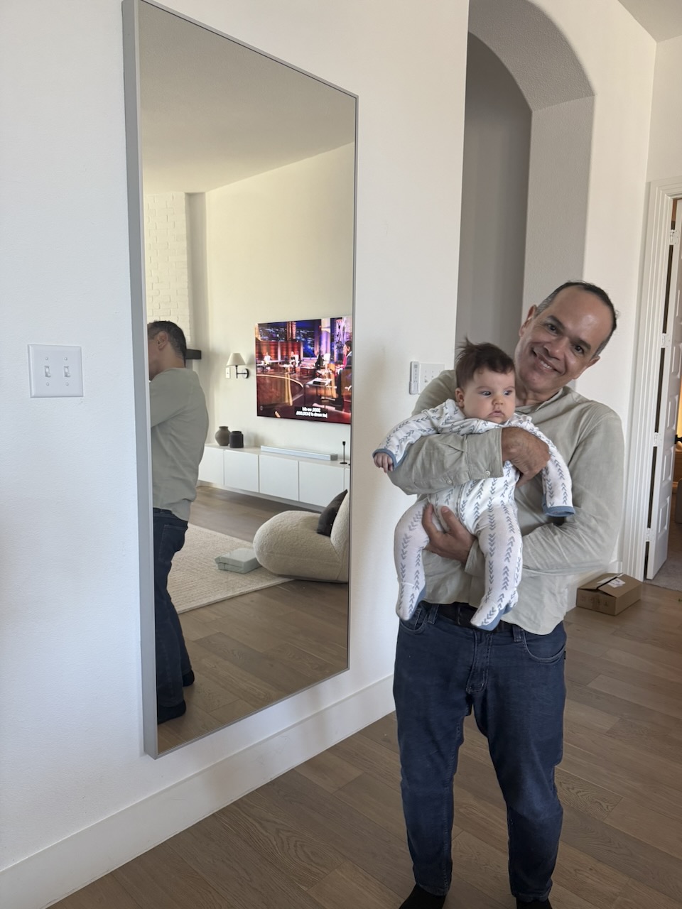 Saulo holding baby Matthew in front of a mirror